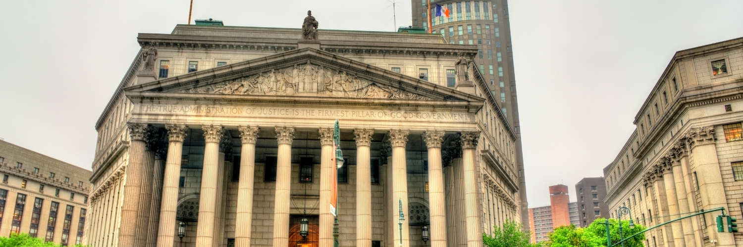 Photograph of a Roman style marble courthouse against a gray sky.