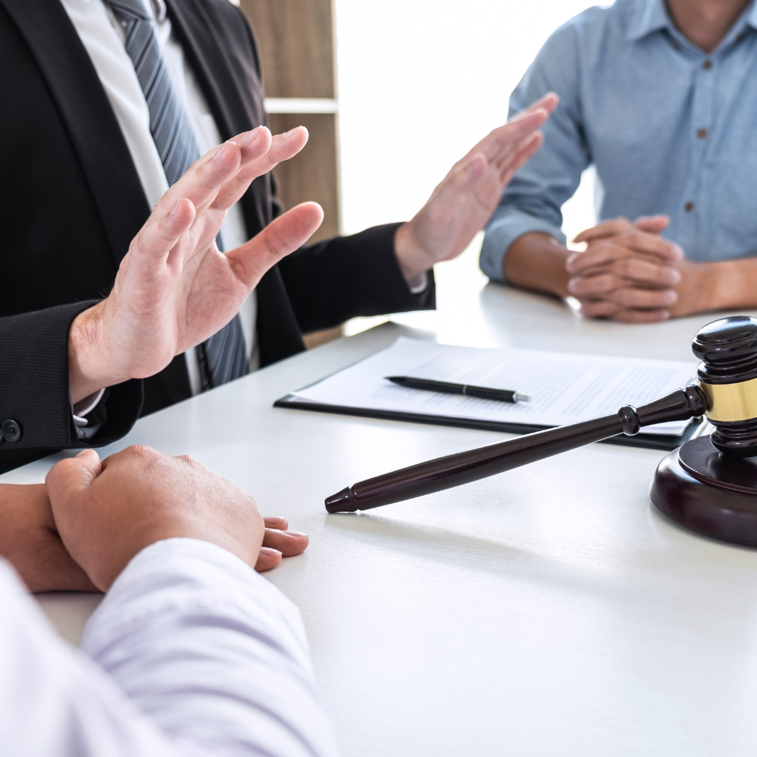 Photograph of 3 business people seated at a table with a document and a judge's gavel on the table.