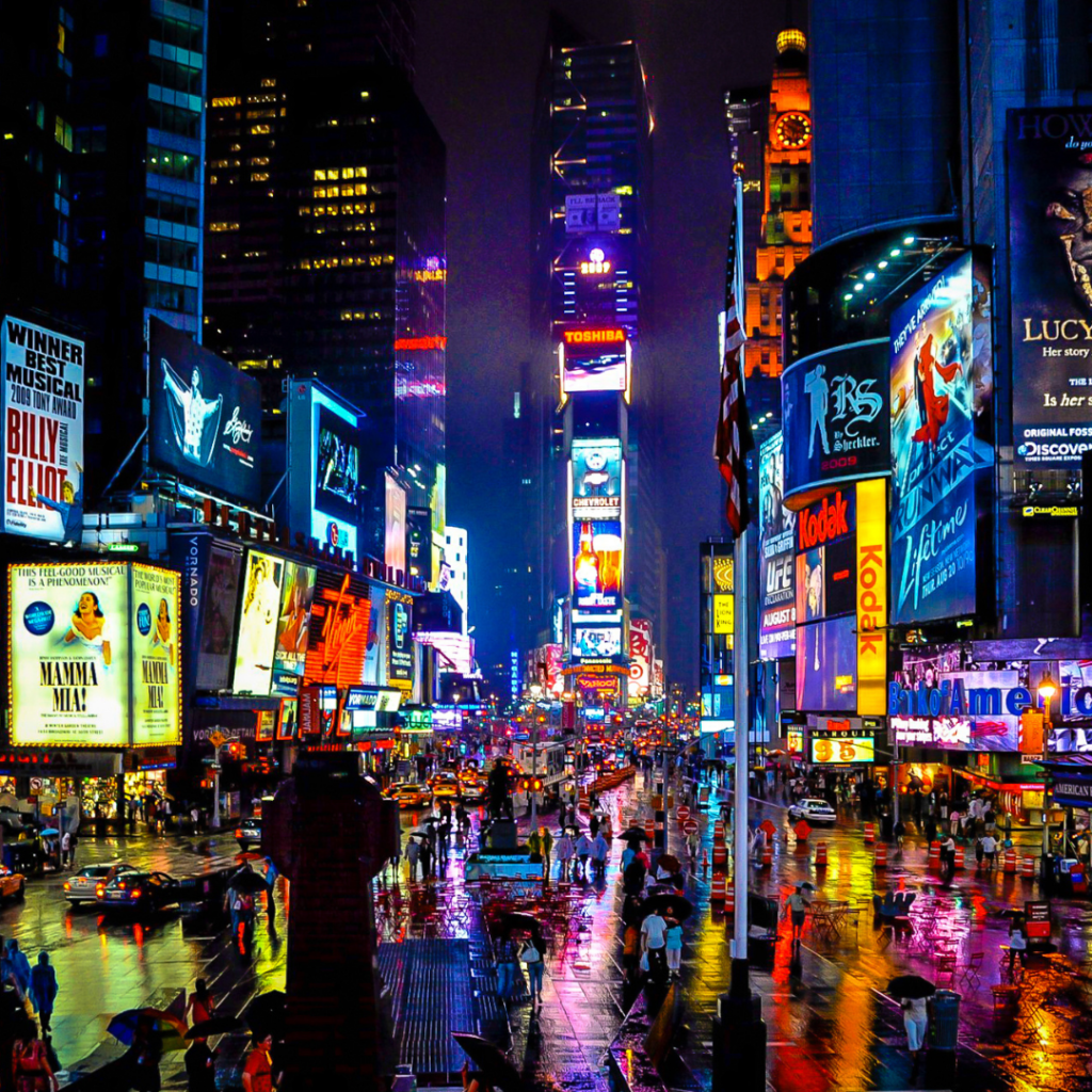 A photograph of New York City's Times Square at night with many brightly colored lights and signs.