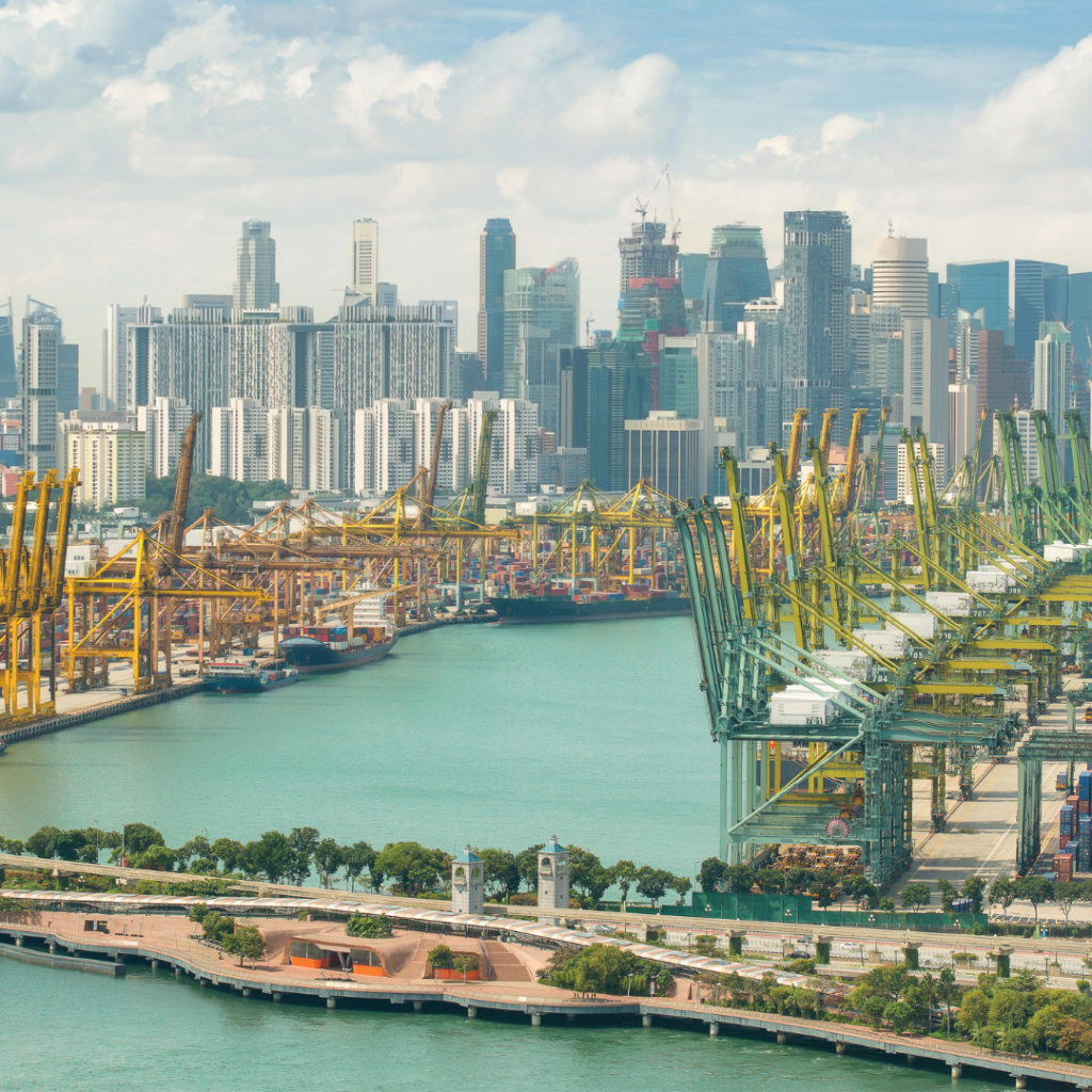 A photograph of shipping port with cargo tankers, with a city skyline in the background.