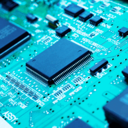 Technology Photograph of multiple black microchips on a green circuit board.