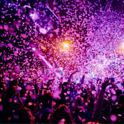 Music Industry & Musicians Photograph of a crowd celebrating at night with purple confetti in the air.