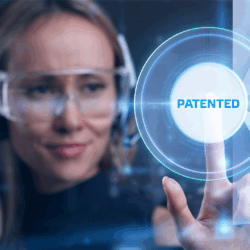 Patent Litigation A photograph of a woman wearing safety glasses and pressing her finger on a button that says "Patented."