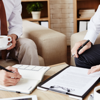 Special Client Advisory Services — Legal & Business Practices Photograph of two men sitting in chairs, holding pens, with a document entitled "Contract."